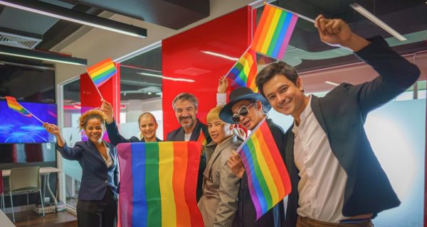 diverse group of business people (man, woman, gay, transgender, lesbian, asian, caucasian, african american, lgbtq) with rainbow flag on hand combine together as teamwork in office, selective focused